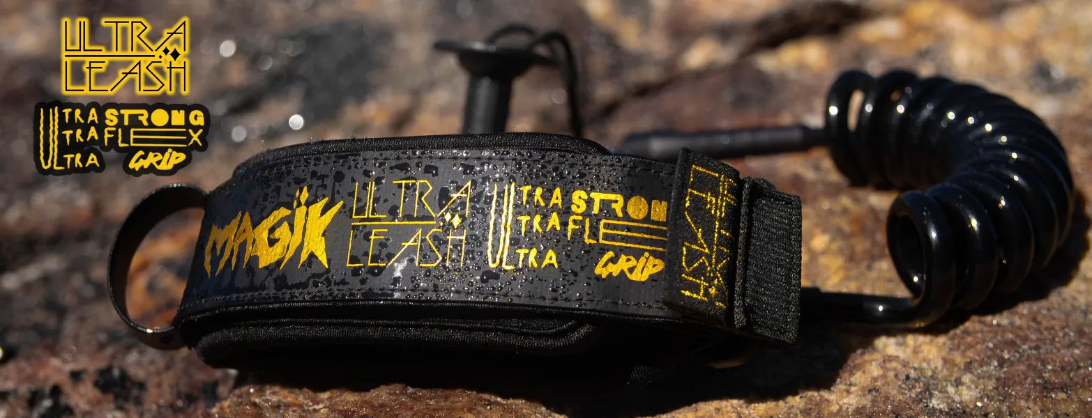 Leash Magik Ultra Leash, com punho de neoprene e cabo espiralado, apoiado sobre pedras molhadas